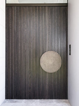 Contemporary Ribbed Wood Pivot Entry Door with Distinctive Metallic Disc Handle