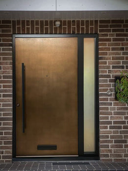 Contemporary Metallic Entry Pivot Door Featuring Sleek Black Hardware Accents